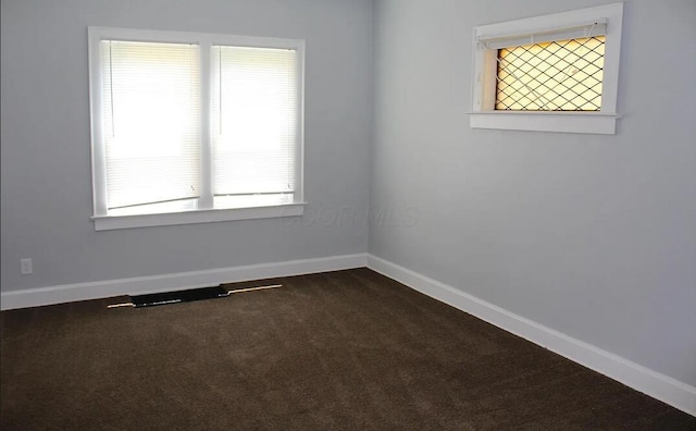 unfurnished room with dark colored carpet and baseboards