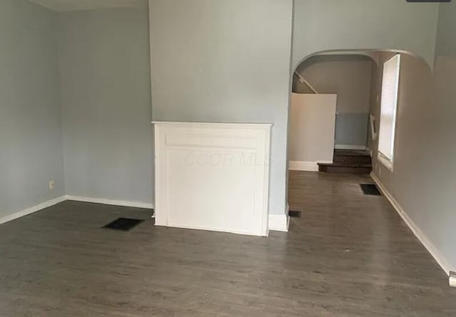 spare room featuring baseboards, dark wood-style flooring, and visible vents