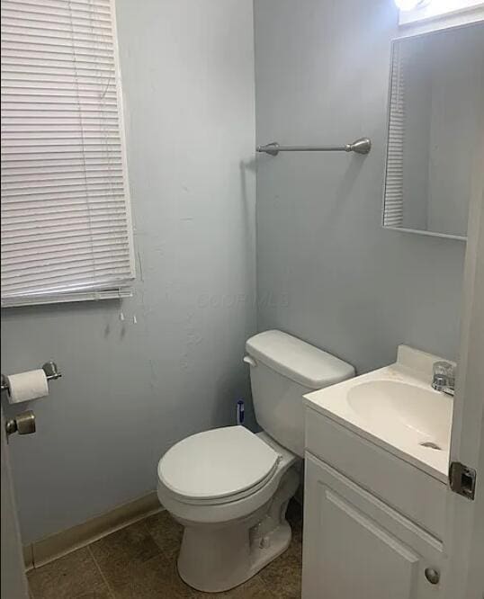 half bathroom featuring vanity, toilet, and baseboards