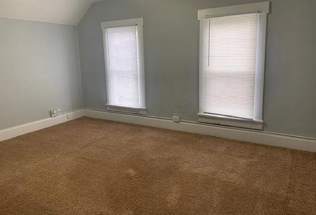 empty room featuring carpet, baseboards, and lofted ceiling
