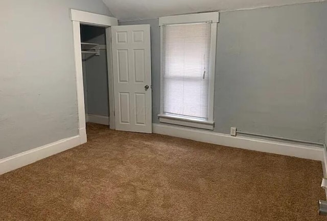 unfurnished bedroom featuring baseboards, carpet flooring, a closet, and vaulted ceiling