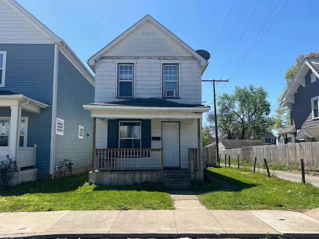 view of front of property with a porch, fence, and a front lawn