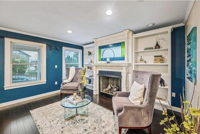 living area with baseboards, ornamental molding, a fireplace, and wood finished floors