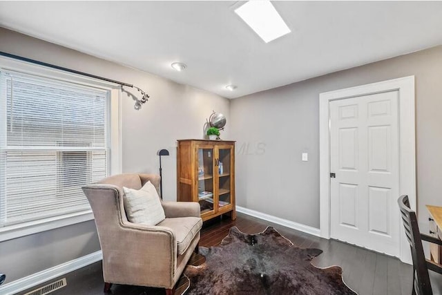 sitting room with baseboards, visible vents, and wood finished floors