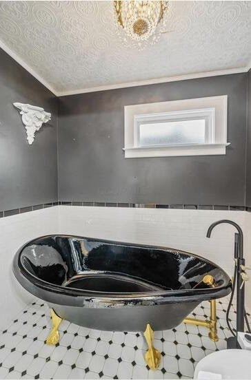 interior details featuring a textured ceiling, a bathing tub, and ornamental molding