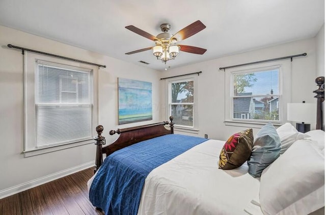 bedroom with ceiling fan, baseboards, visible vents, and wood finished floors