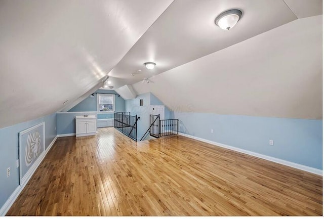 bonus room with baseboards, lofted ceiling, and hardwood / wood-style flooring