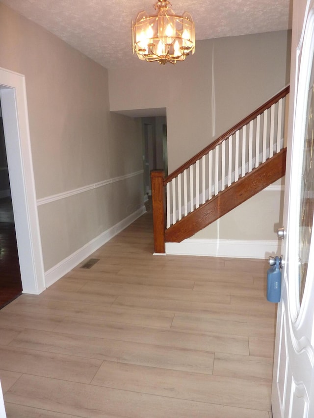 201 N Warren Ave, Columbus, OH 43204 - entryway with stairway, a textured ceiling, a notable chandelier, and wood finished floors