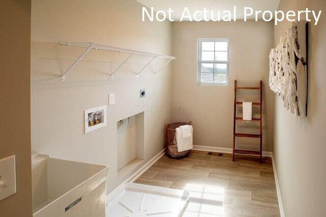 clothes washing area featuring laundry area, hookup for an electric dryer, light wood-style flooring, washer hookup, and baseboards