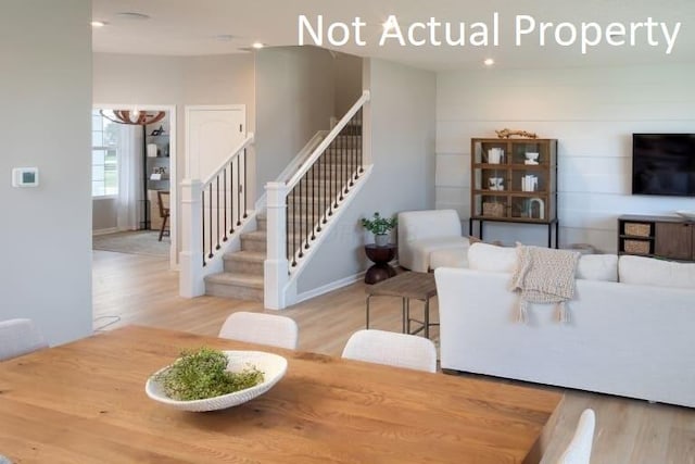 living room with a chandelier, wood finished floors, baseboards, and stairs