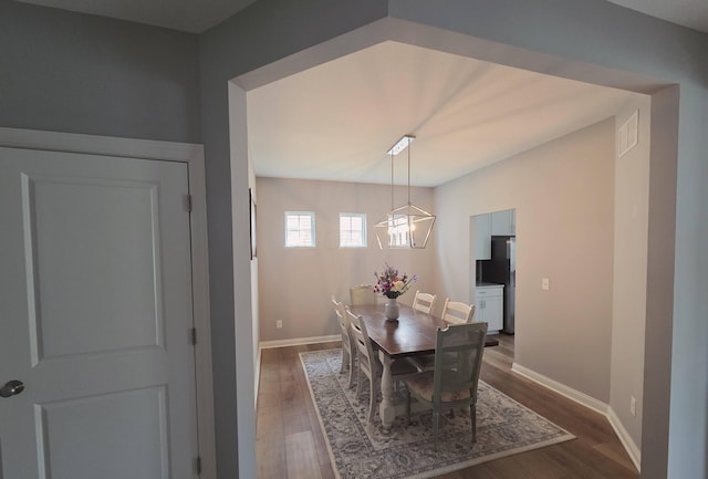 dining area with baseboards, dark wood finished floors, an inviting chandelier, and visible vents