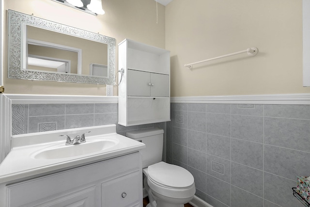 3935 Hillman Rd W, Columbus, OH 43207 - bathroom featuring toilet, tile walls, vanity, and a wainscoted wall