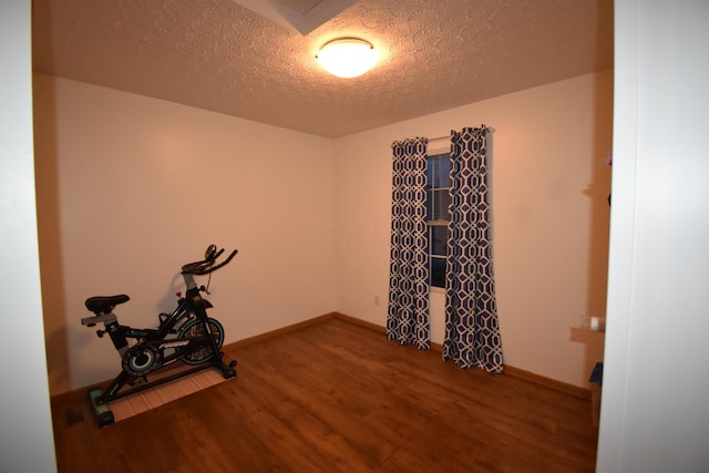 workout area with a textured ceiling, wood finished floors, and baseboards