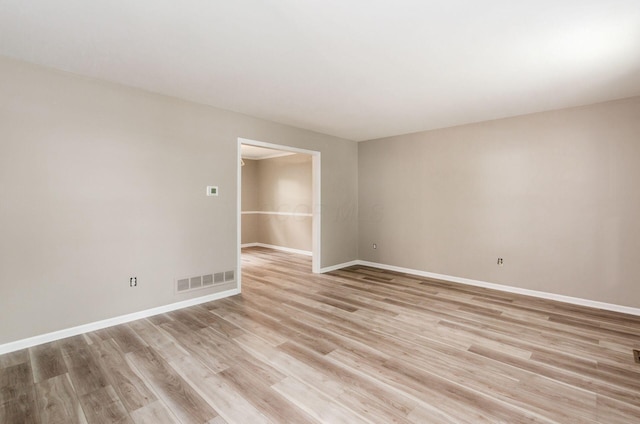 empty room featuring light wood-style floors, visible vents, and baseboards