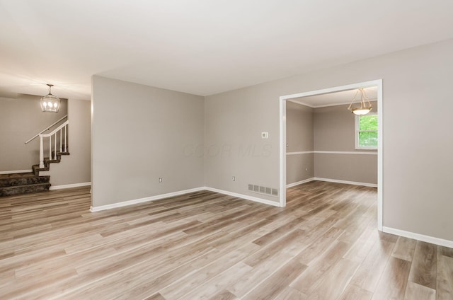 unfurnished room with light wood finished floors, stairs, baseboards, and visible vents