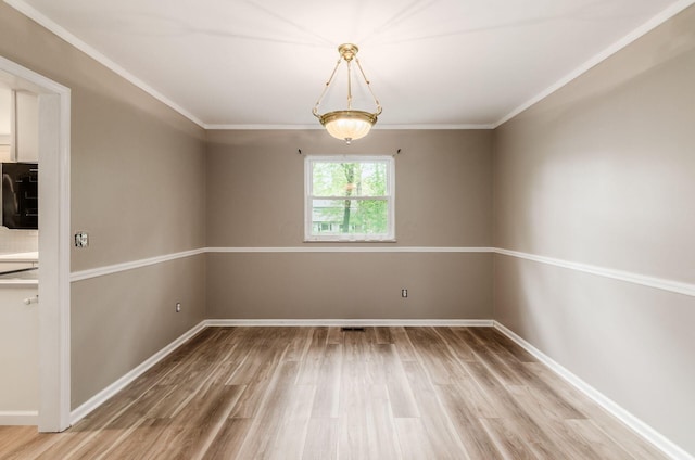 unfurnished room featuring ornamental molding, light wood-style flooring, and baseboards