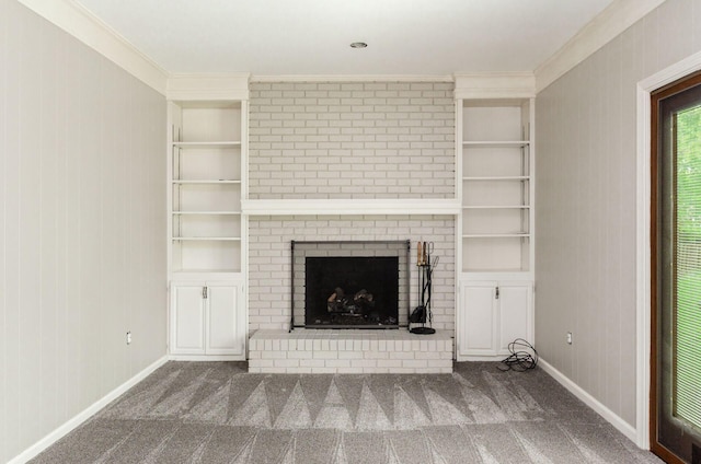 unfurnished living room featuring crown molding, built in shelves, and a brick fireplace