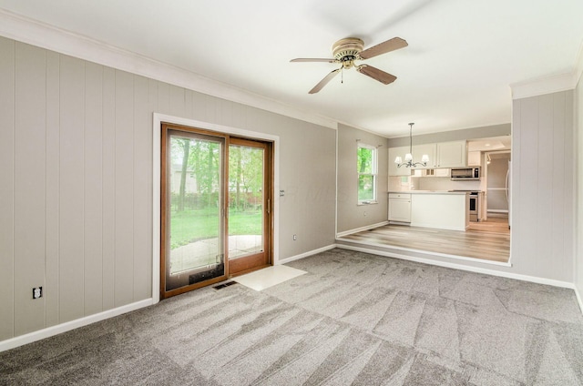unfurnished living room featuring light colored carpet, crown molding, baseboards, and ceiling fan with notable chandelier