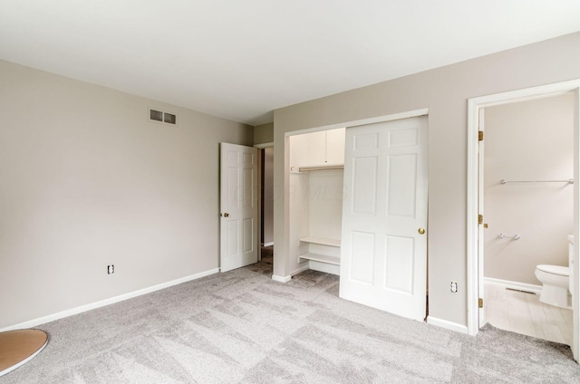 unfurnished bedroom with a closet, connected bathroom, visible vents, and light colored carpet