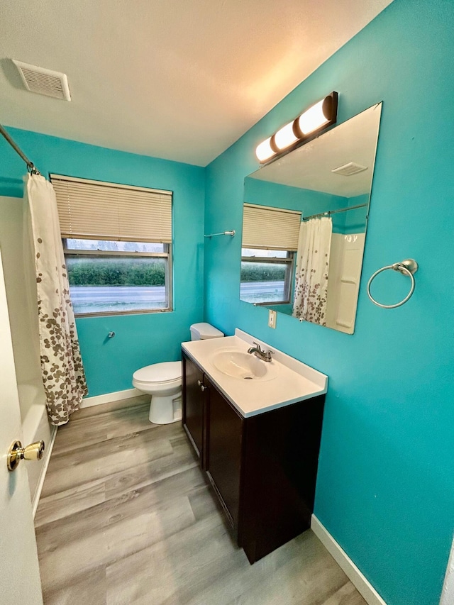 full bath with toilet, baseboards, vanity, wood finished floors, and shower / tub combo