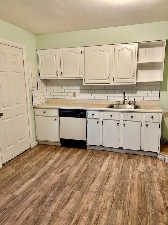 kitchen featuring white dishwasher, a sink, white cabinets, and wood finished floors