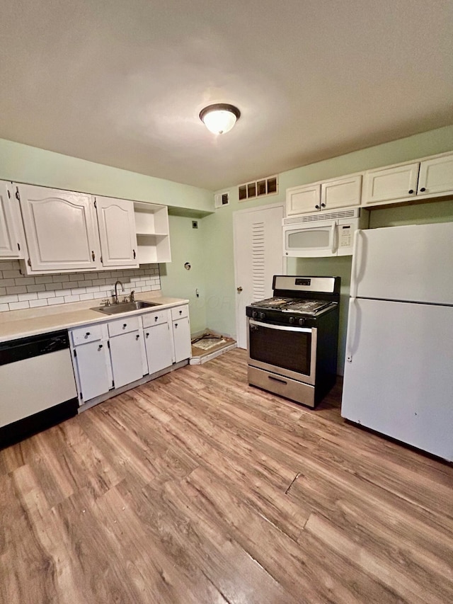 kitchen with white appliances, a sink, white cabinetry, and light wood-style floors