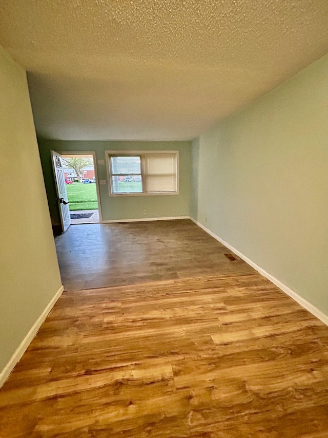 spare room featuring wood finished floors, baseboards, and a textured ceiling