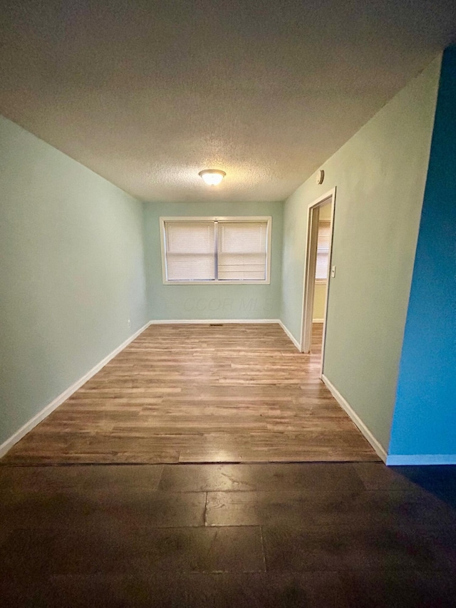 unfurnished room featuring wood finished floors, baseboards, and a textured ceiling