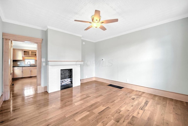 661-663 Beech St, Columbus, OH 43206 - unfurnished living room with a ceiling fan, a fireplace, light wood-type flooring, ornamental molding, and a sink