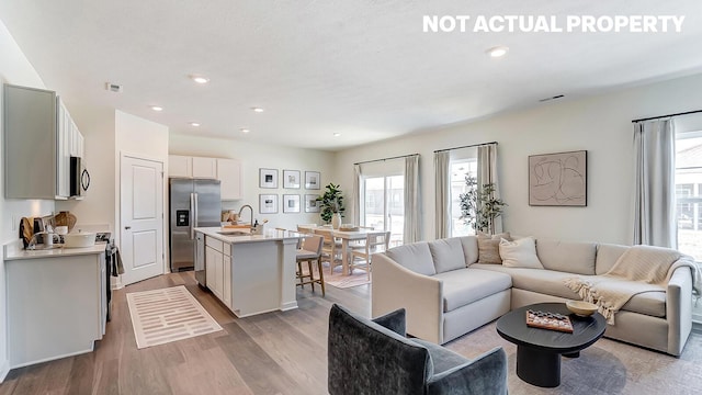 living room featuring a wealth of natural light, light wood-style floors, visible vents, and recessed lighting