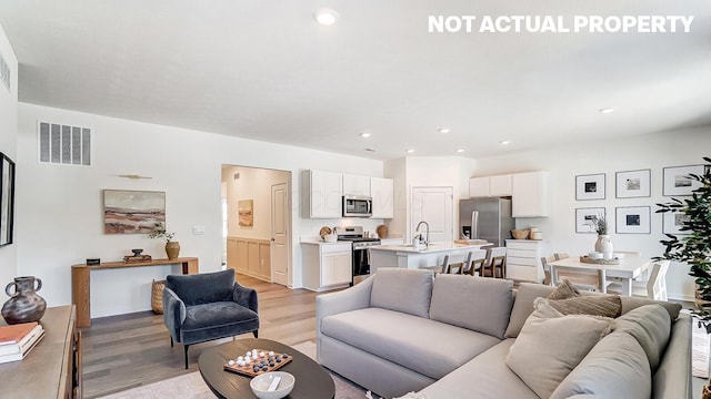 living room with recessed lighting, light wood-style flooring, and visible vents