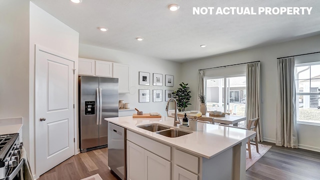 kitchen featuring plenty of natural light, a sink, wood finished floors, white cabinets, and appliances with stainless steel finishes