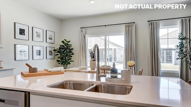 kitchen featuring white cabinets, light countertops, plenty of natural light, and a sink