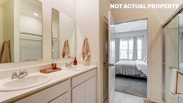 ensuite bathroom with double vanity, ensuite bath, a shower with door, and a sink