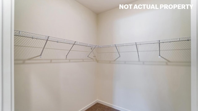 walk in closet featuring dark carpet