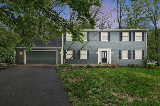 colonial-style house featuring a front lawn, driveway, and a garage