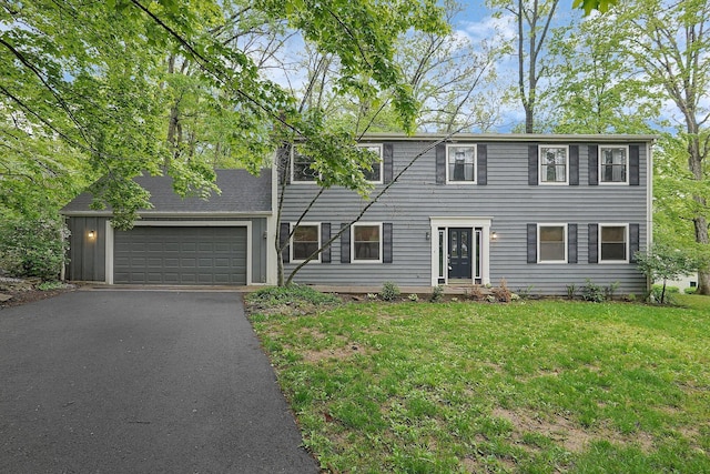 colonial house featuring a front lawn, driveway, and a garage