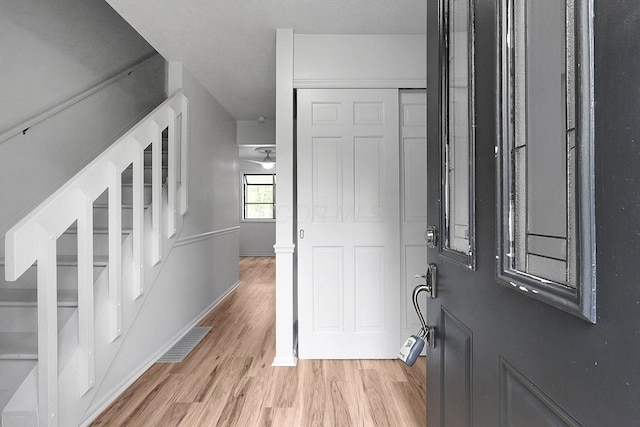 foyer entrance with light wood-style flooring, stairs, baseboards, and visible vents