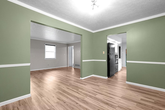 unfurnished room featuring wood finished floors, ornamental molding, a textured ceiling, visible vents, and baseboards