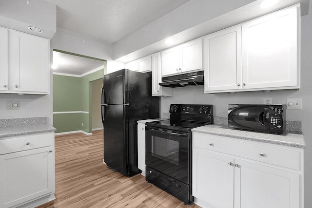 kitchen with under cabinet range hood, light wood finished floors, white cabinetry, and black appliances
