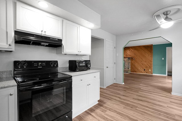 kitchen with black appliances, under cabinet range hood, white cabinets, baseboards, and light wood-style floors