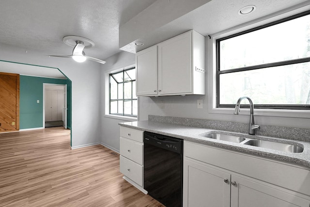 kitchen with light wood-style flooring, a textured ceiling, black dishwasher, a sink, and white cabinetry