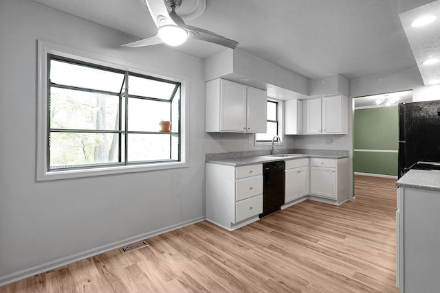 kitchen with a sink, white cabinetry, baseboards, and black appliances