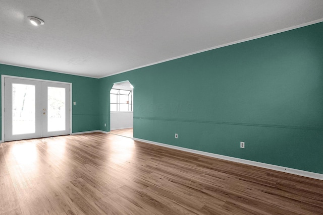 empty room with crown molding, baseboards, french doors, and wood finished floors