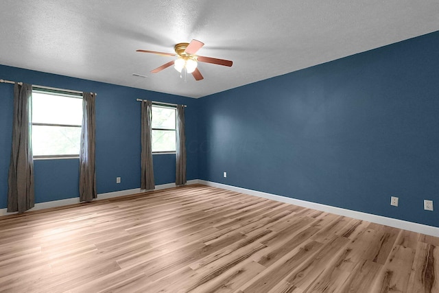 empty room featuring light wood-type flooring, baseboards, ceiling fan, and a textured ceiling