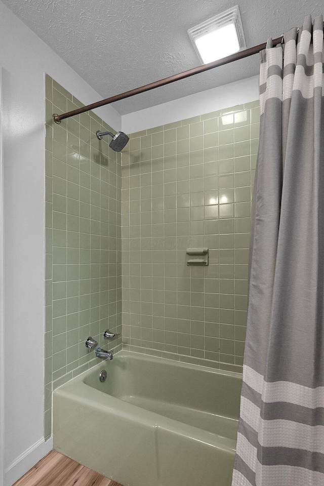 full bath featuring baseboards, shower / bath combination with curtain, a textured ceiling, and wood finished floors