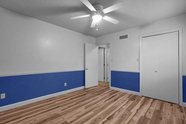 unfurnished bedroom with baseboards, ceiling fan, visible vents, and wood finished floors