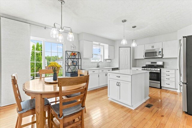830 Avalon Dr, Pickerington, OH 43147 - kitchen with appliances with stainless steel finishes, a textured ceiling, light countertops, white cabinetry, and a kitchen island