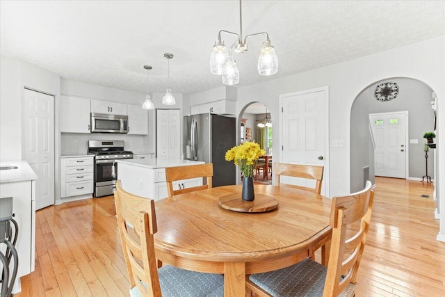 830 Avalon Dr, Pickerington, OH 43147 - dining area with arched walkways, a chandelier, and light wood-style flooring