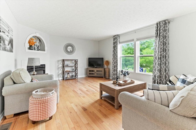 830 Avalon Dr, Pickerington, OH 43147 - living area with light wood finished floors, a textured ceiling, a fireplace, and baseboards